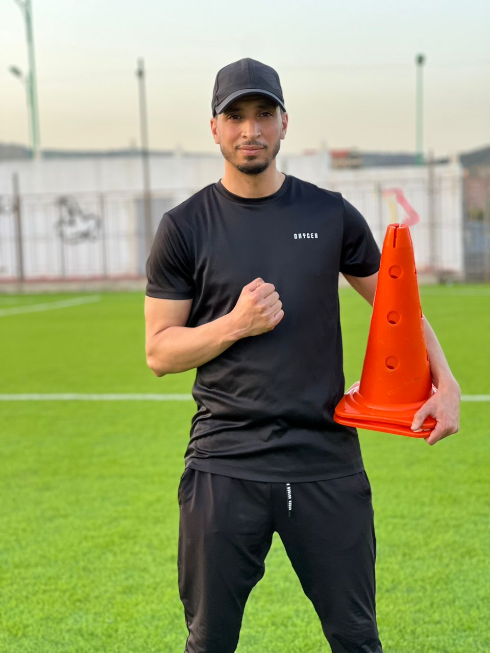 Coach Sohaib on the pitch holding a training cone